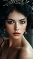 A close-up portrait of a woman with dark hair and blue eyes, adorned with a silver crown, set against a dark background.