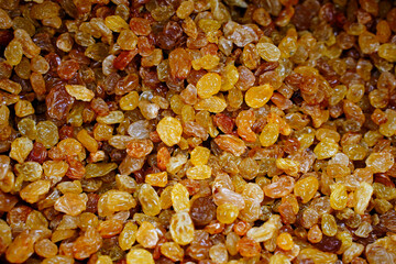 Dried yellow golden raisins as background. Pile of sweet and dry raisins for dessert. Organic golden raisins texture. Top view.