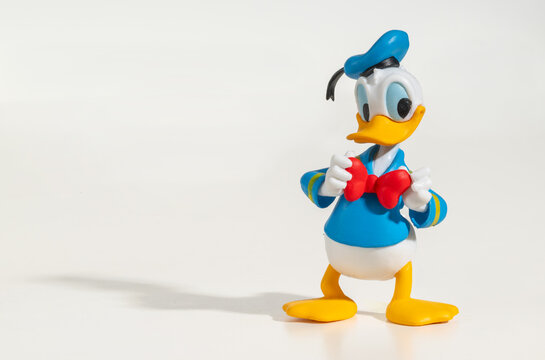 Donald Duck figurine adjusting his red bow tie on white background