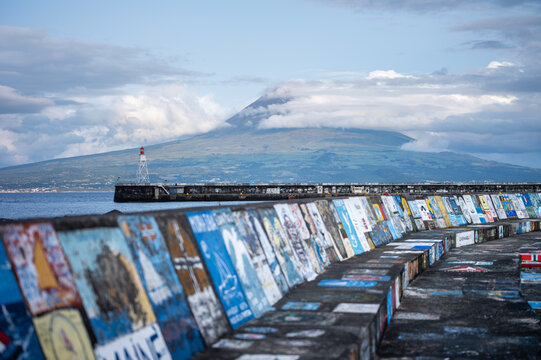 13 August 2021: Azores harbor, Faial, with a lighthouse, painted seawall.
