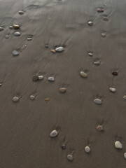 A coastline with wet sand in which small stones are partially sunken