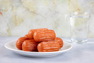 Traditional Turkish dessert tulumba on a plate with a glass of water.Tulumba dessert, fried in oil and soaked in syrup
