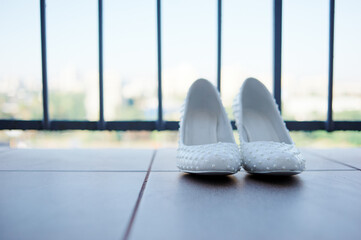 Elegant White Bridal Shoes With Embroidered Details on a Bright Balcony..
