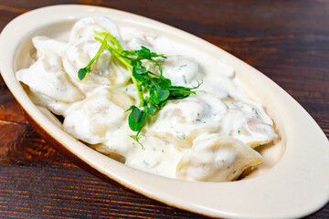 Dumplings served in creamy sauce with herbs on wooden table