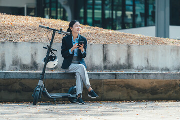 Female professional resting on concrete bench, scrolling smartphone beside electric scooter in modern urban landscape with sustainable elements © PaeGAG