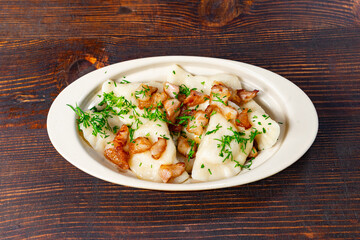 Delicious dumplings topped with crispy bacon on a wooden table