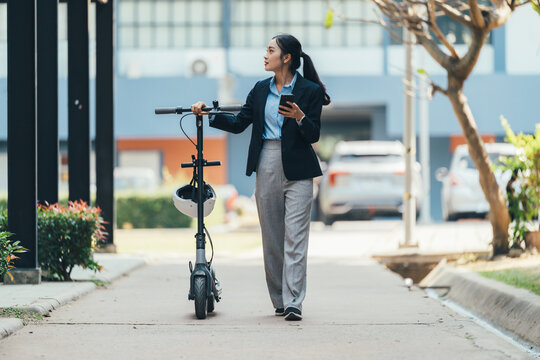 Professional female commuting on electric scooter, navigating busy city sidewalk, smartphone in hand, representing contemporary urban mobility and sustainable transportation trends - Powered by Adobe