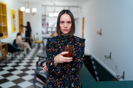 Woman Holding Glass in Stylish Interior with Artistic Decor..
