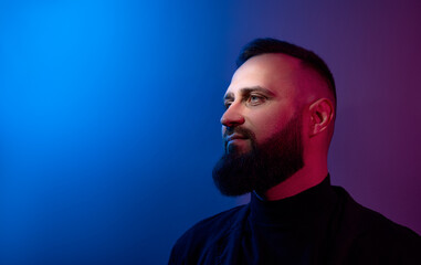 Studio portrait with colorful light of young handsome bearded man.