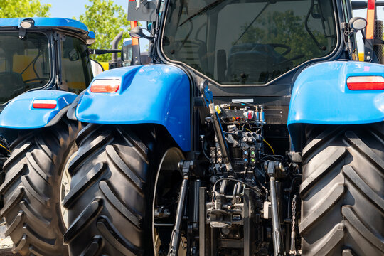 Blue tractors parked at a dealership viewed from the rear. Technical service of farm machinery.