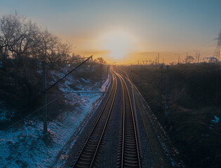 A breathtakingly tranquil view of the railway tracks winding through a serene winter landscape at...
