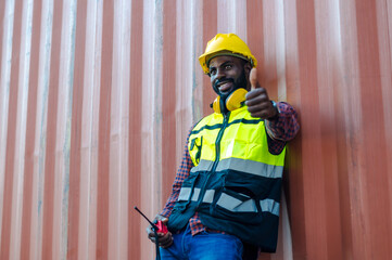 Black man worker with safety helmet working in container shipyard for import export distribution...