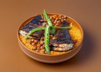 Tunisian dish - Couscous with fried seabass fish on a brown plate