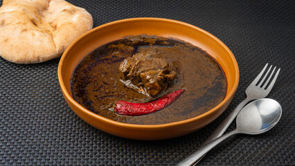  Traditional Tunisian molokhia is made with jute leaves and beef, with red pepper and flatbread on...