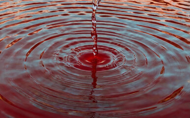 circles on the water diverging on the water with a funnel in the centre in beautiful red water