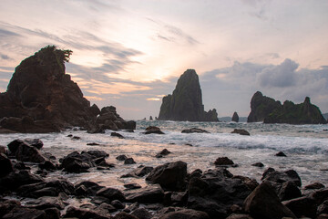 A serene scene at a rocky beach during sunset in Blitar, East Java, Indonesia.