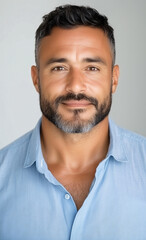 Obraz premium Confident Man Portrait: A headshot of a middle-aged man with a warm, friendly smile, showcasing his confidence and approachability. He has salt-and-pepper stubble and dark eyes.