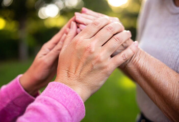 A macro shot of a young girl (White) and her grandmother's intertwined hands, with a focus on the hands and their smiles, taken from eye level.