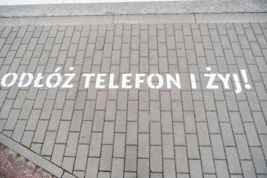 A brick walkway with odloz telefon i zyj painted on it
