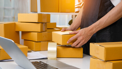 Small business owner packing boxes for online orders ready for shipping, Man taping cardboard boxes...