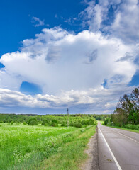 Large cloud is in the sky above a road