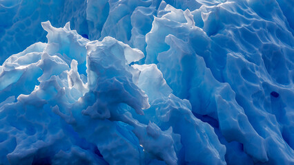 Naklejka premium Detail of a blue glacial iceberg in Northeast Greenland National Park. Huge chucks of ice calve from he glacier and are gradually weather by wind and water to make amazing abstract ice sculptures.