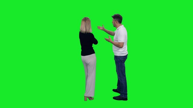 Back view of adult man something explaining to stylish woman standing on green chroma key background, 4k pre-keyed footage
