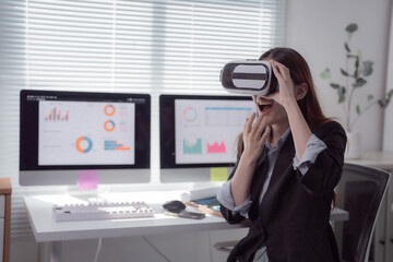 Businesswoman is sitting at her desk, wearing a virtual reality headset and looking surprised at interactive charts displayed on her computer screens