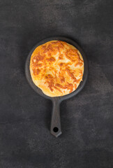 Khachapuri. Cheese pie. Flatbread with cheese.  On a wooden board. Dark background. Top view