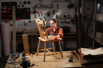 Carpenter woman measuring old chair for restoration working with antique furniture in workshop. Furniture restoration and diy concept.