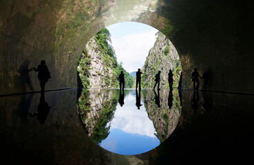 Tourists enjoy the view at the end of a tunnel with an inverted landscape of Kiyotsukyo Gorge...