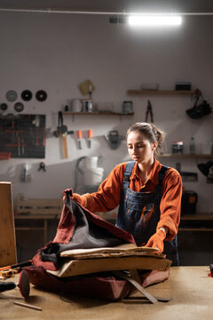 Young woman in workshop restoring old furniture by upholstering armchair replacing fabric to give fresh look focusing on craftsmanship and detail in refurbishment process