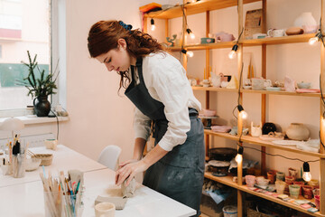 Female artisan molds piece of clay in the art studio. Sculpting clay for making earthenware.