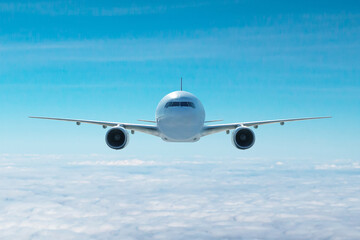 Front view of the white wide body passenger aircraft flying in the air above the clouds