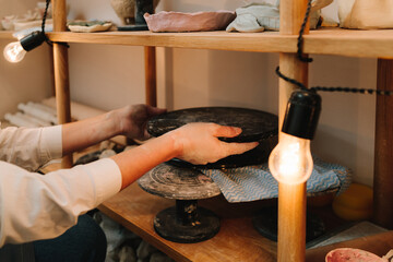 Handmade pottery earthenware on wooden shelves decorated with cozy lights in the ceramic studio.