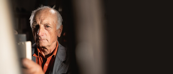 Elderly carpenter or joiner working in safety glasses in a carpentry workshop
