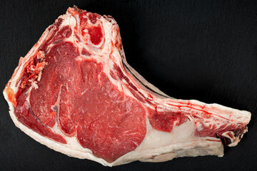 Large raw veal chop on a dark background.