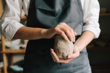 Potter holds a piece of wet clay in their hands, molds it into form. Process of creating ceramic...