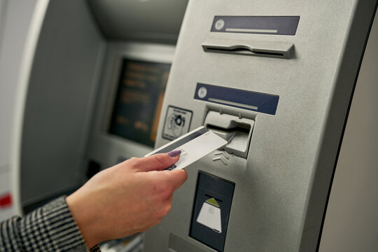 Close-up of a young woman's hand as she smoothly inserts her debit card into the ATM, accessing her financial resources with ease.