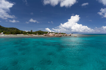 La Digue Ferry Harbour Bay. Ein sonniger Tag auf den Seychellen, das Meer türkisblau. Sicht zum Leuchtturm mit den Felsen bei der Einfahrt zum Hafen.