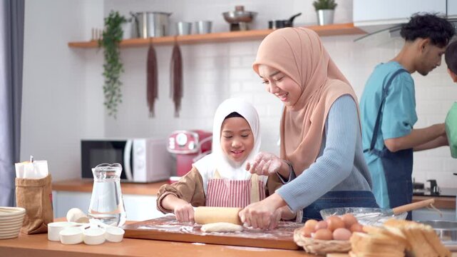 Muslim woman is kneading dough with her daughter to bake bread.