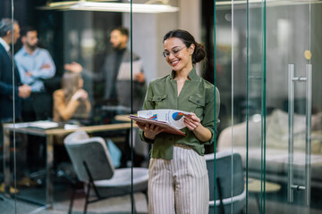 Business woman standing and finishing some paperwork in her office.