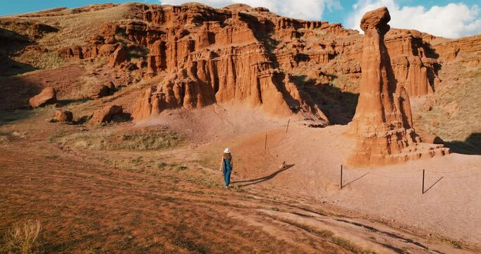 While the traveler girl is wandering around the Narman Fairy Chimneys, the drone takes off and reveals unique geological formations. Red rocks and valleys offer a fascinating atmosphere.