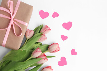 Beautiful tulips, gift box and paper hearts on white background, top view