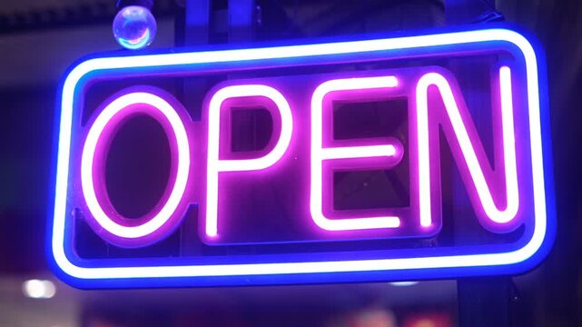 A neon sign that says Open in purple and blue. The sign is lit up and is on a building