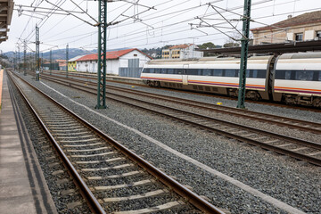 A sleek high-speed train pauses at a railway station, showcasing modern transportation against a...