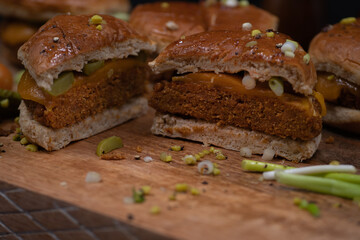 Vegan burgers made with seitan and vegan cheese, pickles on wooden cutting board