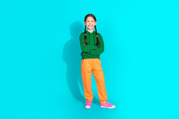 Charming preteen girl posing in colorful outfit against turquoise background, spreading happiness and style