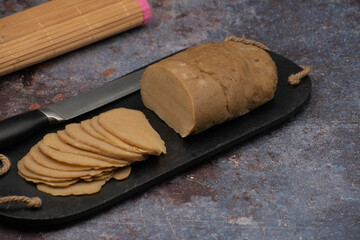 Sliced seitan lunchmeat loaf on  black slate, copy space