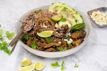 Vegan seitan stir fry bowl with buckwheat, mushroom, pepper and cucumbers